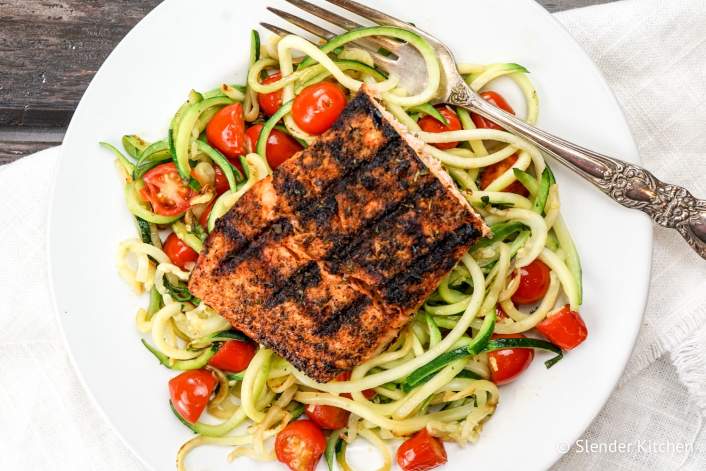 Blackened Salmon with Garlic Zucchini Noodles on a white plate and wooden background.