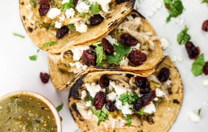 Slow Cooker Turkey Tacos with cilantro, onion, and cranberries on tortillas
