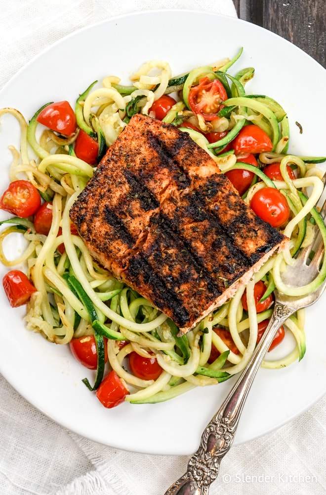 Blackened Salmon with Garlic Zucchini Noodles on a plate with tomatoes.