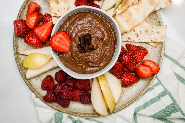 Chocolate hummus in a bowl with fresh fruit.