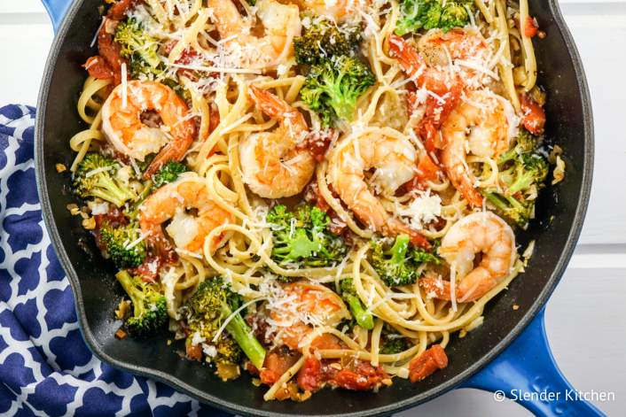 Pasta with lemon, broccoli, tomatoes, and shrimp in a pan.
