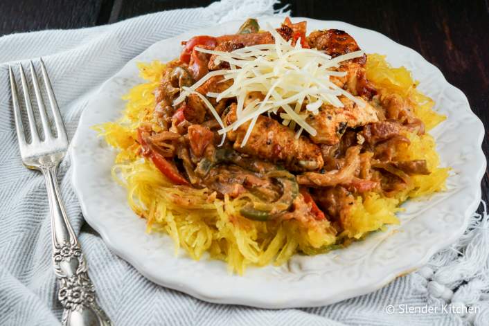 Creamy Cajun chicken over spaghetti squash on plate with fork.