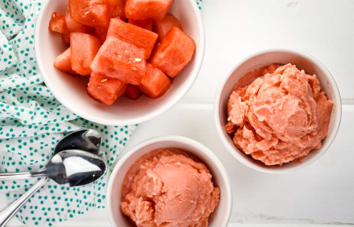 Watermelon ice cream in a bowl with frozen watermelon.
