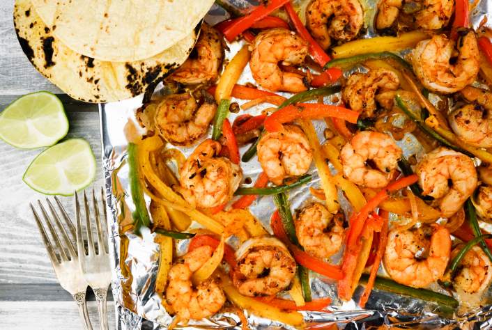 A sheet pan with shrimp, peppers, and onions