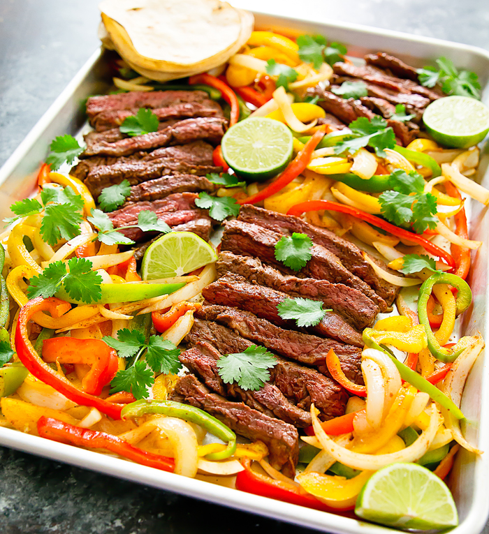 Steak fajitas made on a sheet pan with peppers and onions.