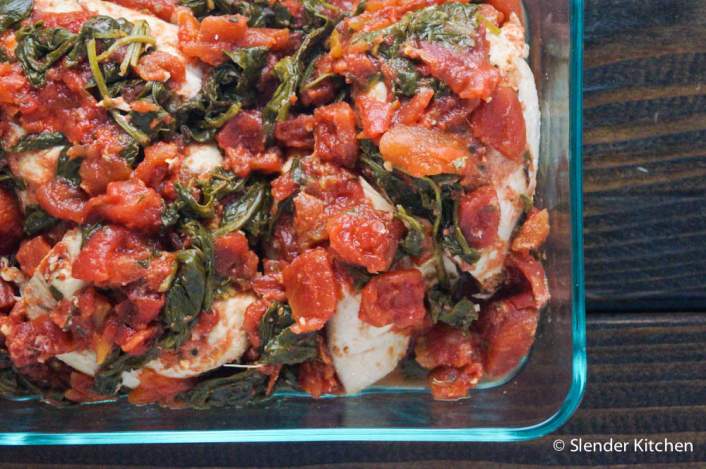 Healthy Crockpot Tomato Balsamic Chicken with spinach in a glass baking dish.