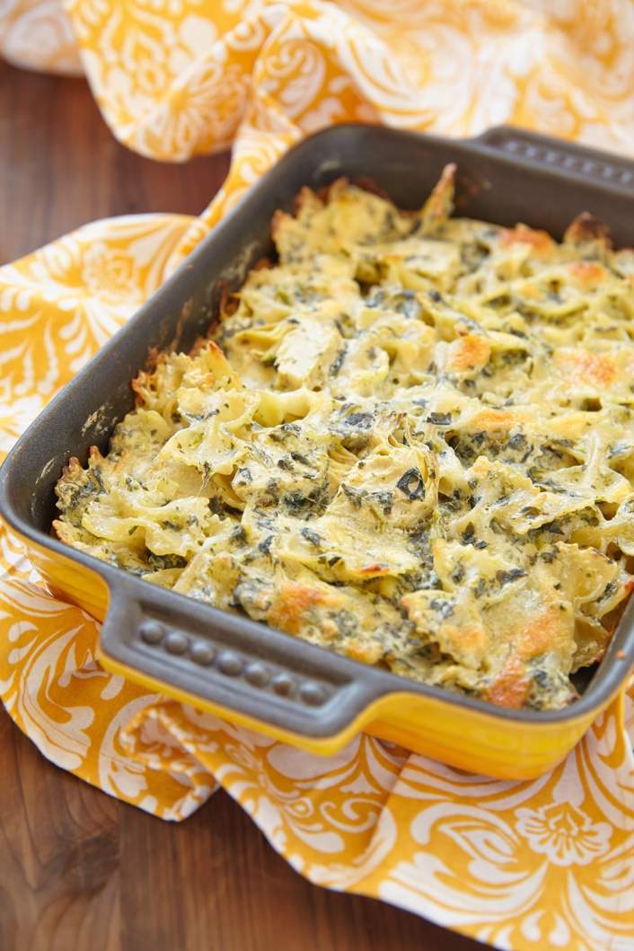 Healthy Spinach Artichoke Pasta in a baking dish with yellow napkin.
